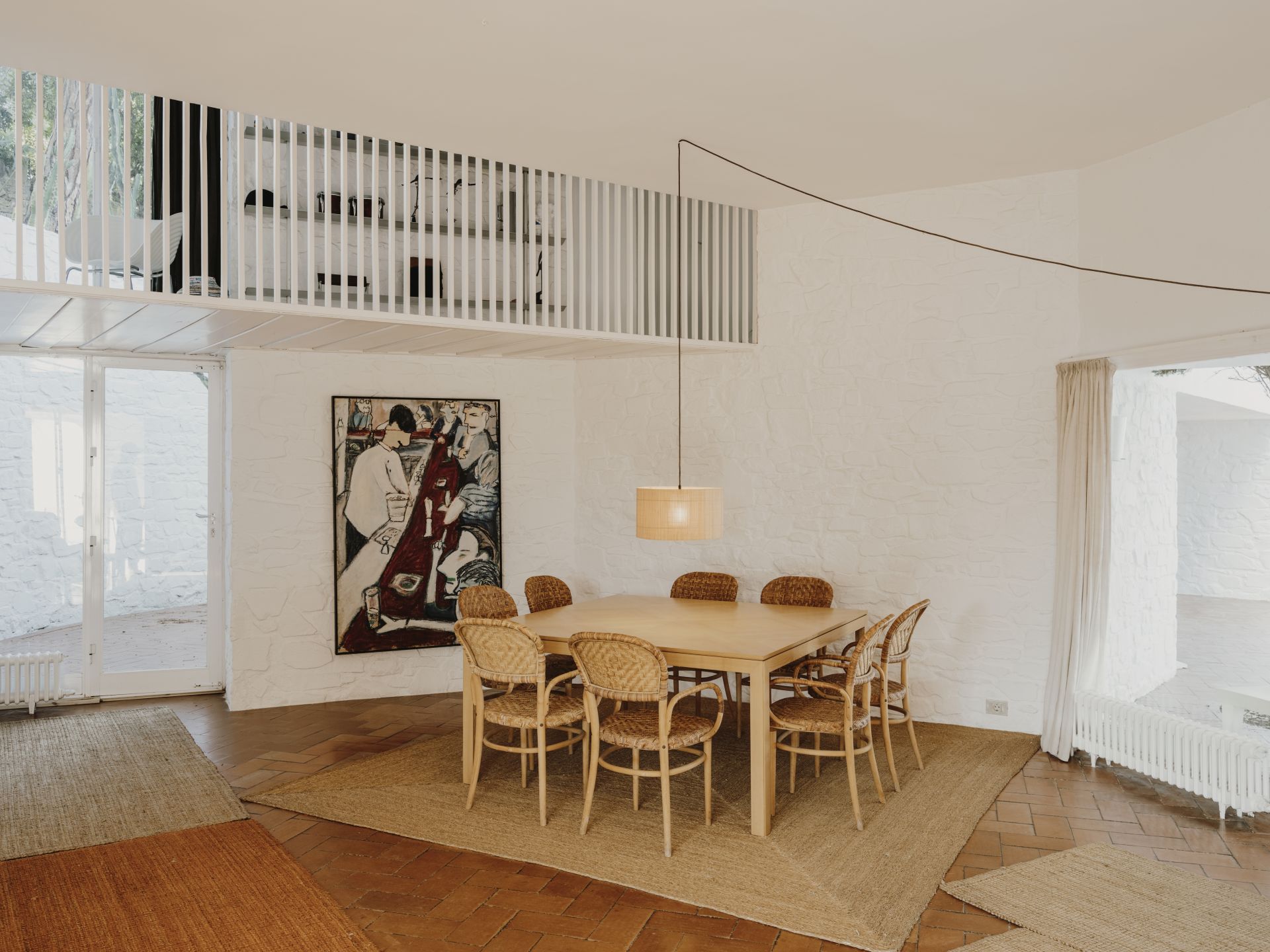 Heller Essbereich mit Holztisch, Rattan-Stühlen, Kunstwerk und gewebtem Teppich für ein modernes, stilvolles Zuhause.