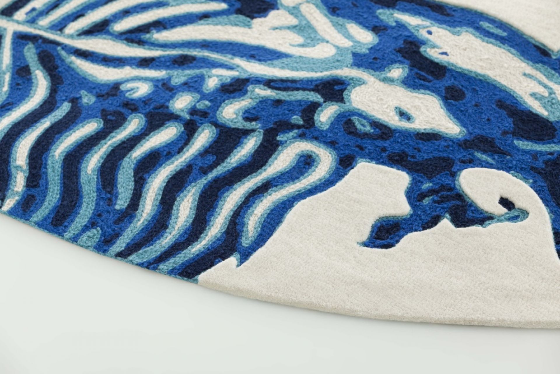 Detailaufnahme des Cadeneta Blue Teppichs von GAN mit blau-weißen, wellenförmigen Mustern. Hochwertiger Wollteppich für Wohnräume.