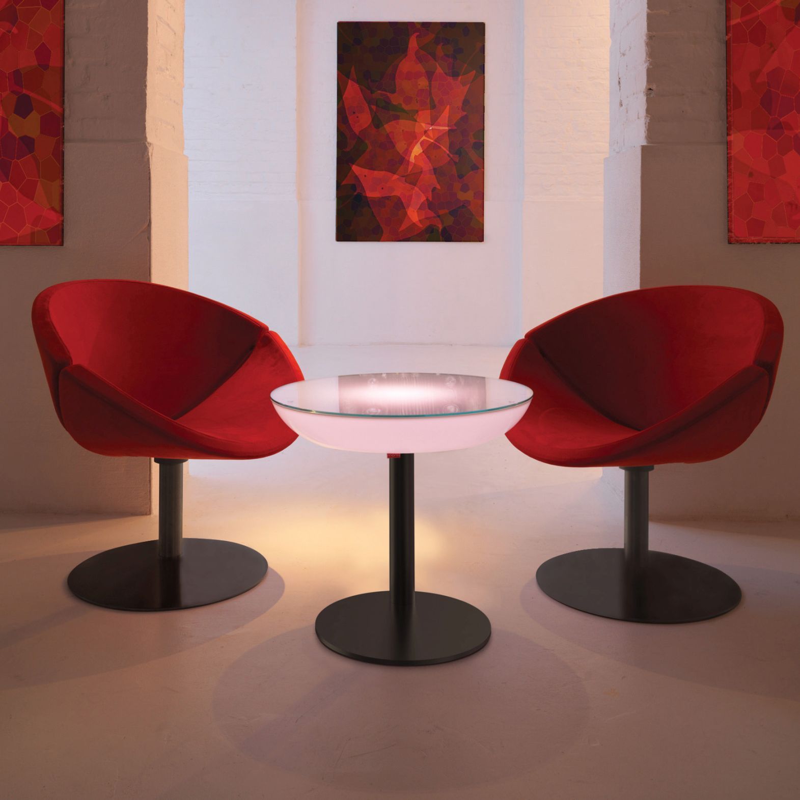 Moree Lounge M57 Leuchttisch als Beistelltisch zwischen zwei roten Sesseln in einem Wohnraum.