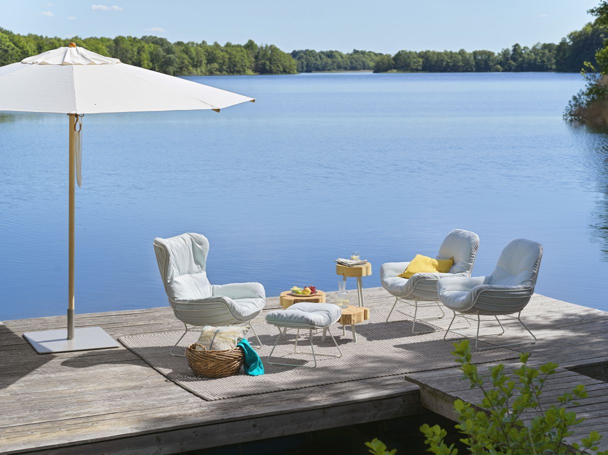 BC 05 Stomp Outdoor Couchtisch von Janua neben Sesseln und Beistelltisch am See.