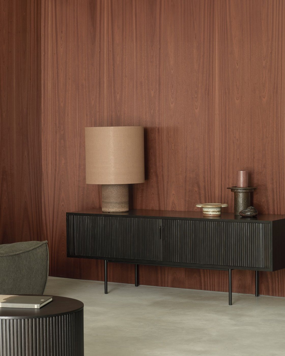 Schwarze Ethnicraft Roller Max TV Anrichte aus Teakholz mit zwei Türen vor einer Holzwand.