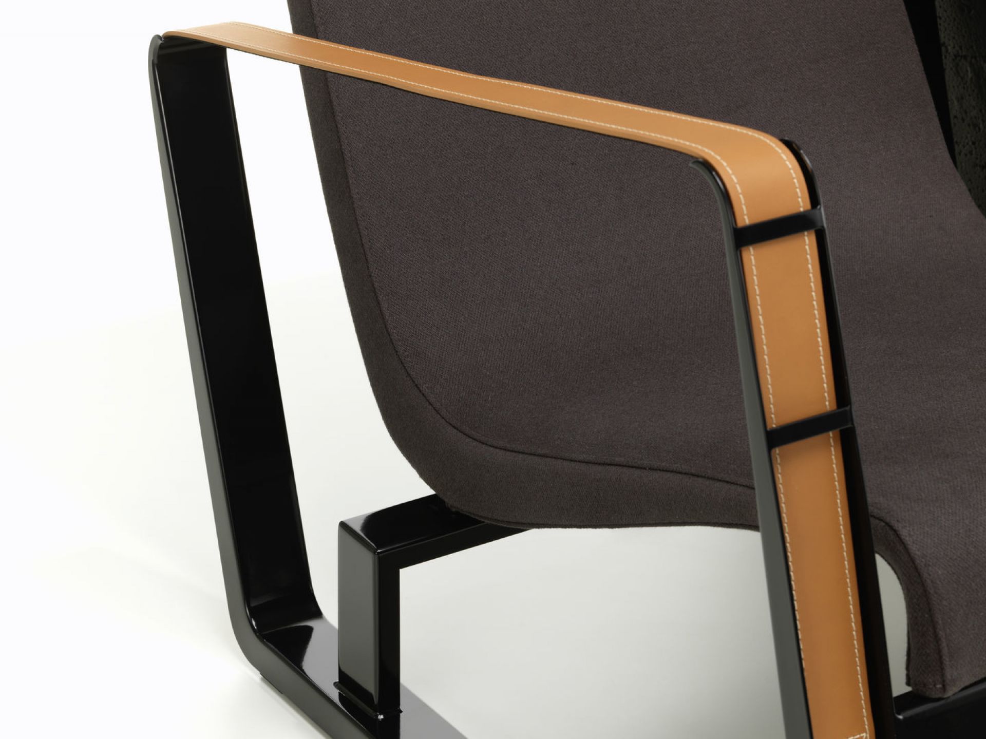 Detailaufnahme des Vitra CitÉ Sessels mit braunem Stoffbezug und Lederarmlehnen auf einem weißen Hintergrund.