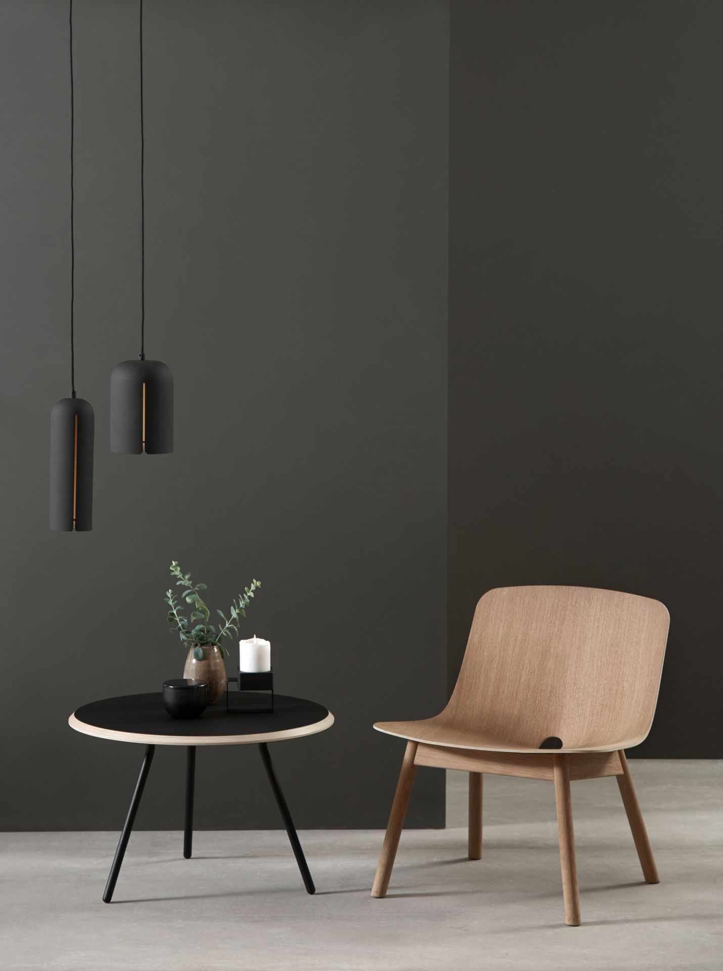 Beiger Soround Coffee Table Couchtisch von Woud mit Dekoration und Holzstuhl vor dunklem Hintergrund.