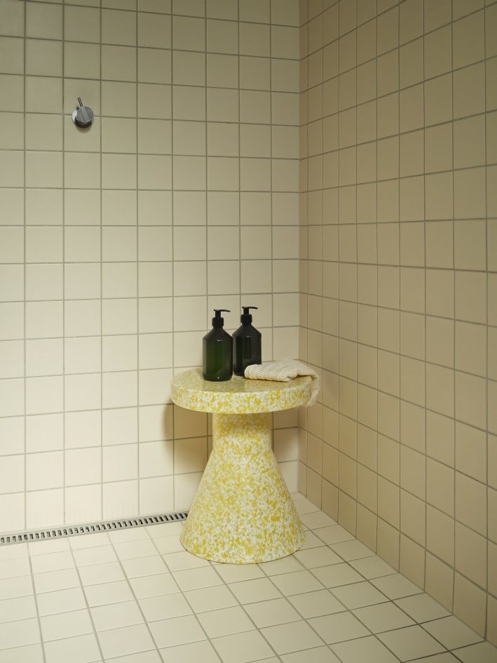 Gelber Bit Stool Cone Hocker von Normann Copenhagen im Badezimmer mit Seifenspendern und Handtuch.