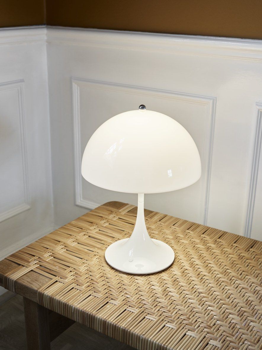 Weiße Panthella 250 Akku LED-Tischleuchte von Louis Poulsen auf einem geflochtenen Tisch.