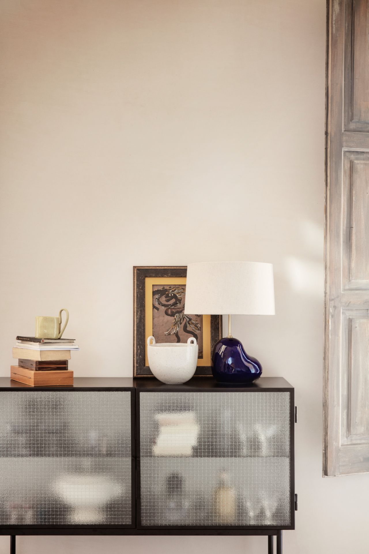 Schwarzes Haze Sideboard von Ferm Living mit strukturierten Glastüren und Deko-Objekten auf der Oberseite.