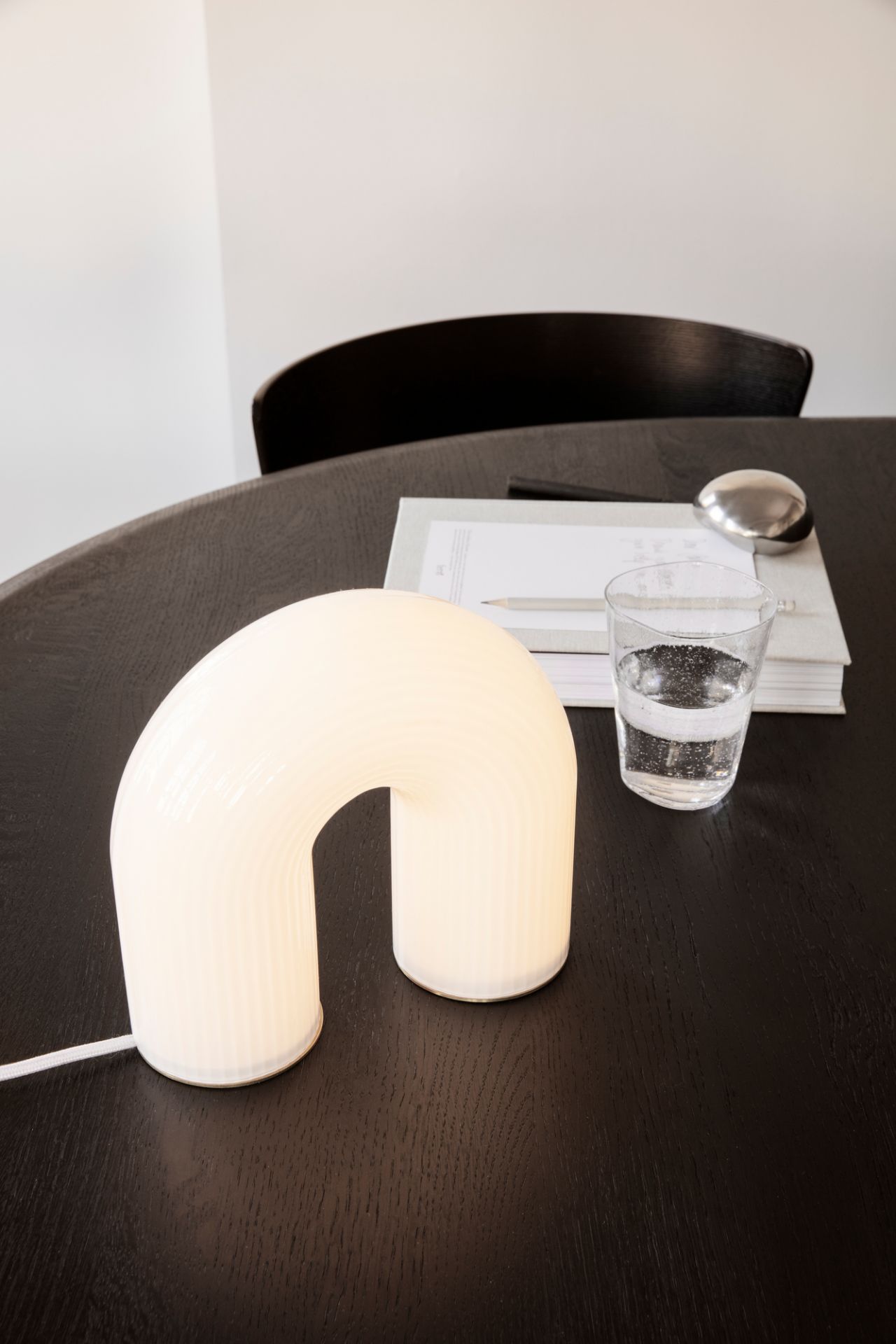 Nahaufnahme der modernen Vuelta Tischleuchte von Ferm Living auf einem dunklen Holztisch.