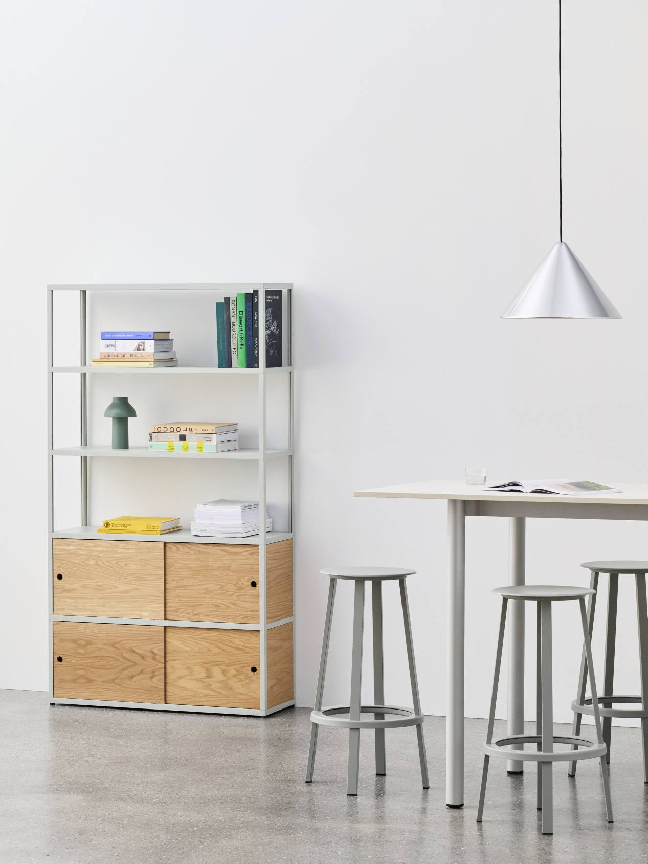 Annex Table Overhang Esstisch von Hay mit Barhockern und Bücherregal in einem modernen Esszimmer.