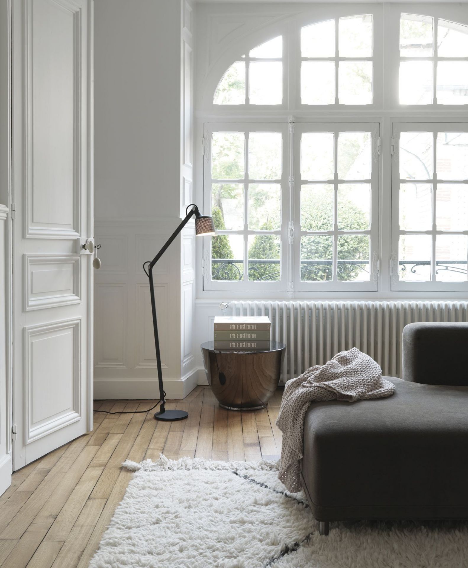 Schwarze Vipp Boden Leselampe im modernen Wohnzimmer mit Sofa, Teppich und großem Fenster für gemütliche Beleuchtung.