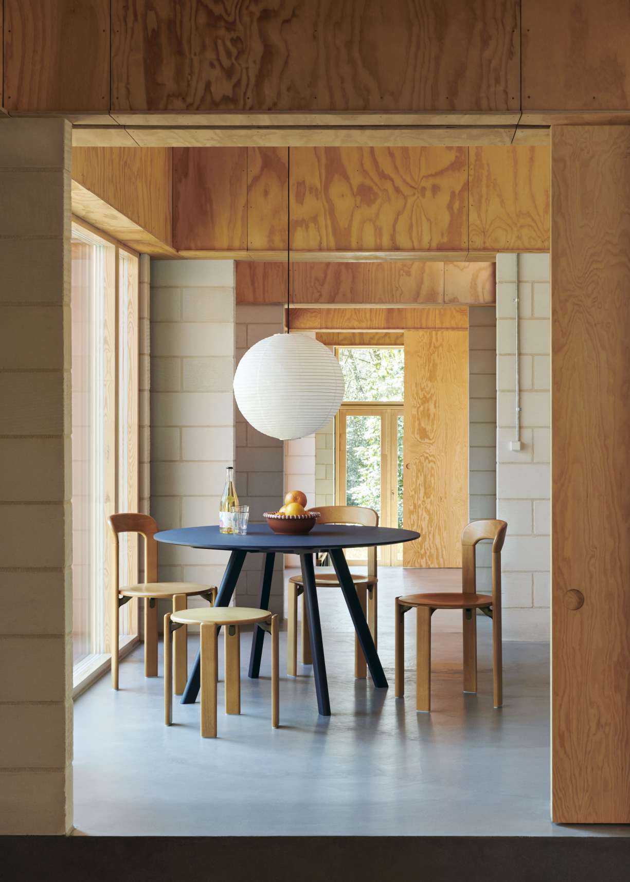 Runder Copenhague Table CPH 25 Esstisch von Hay in blau mit Holzstühlen und Obstschale.