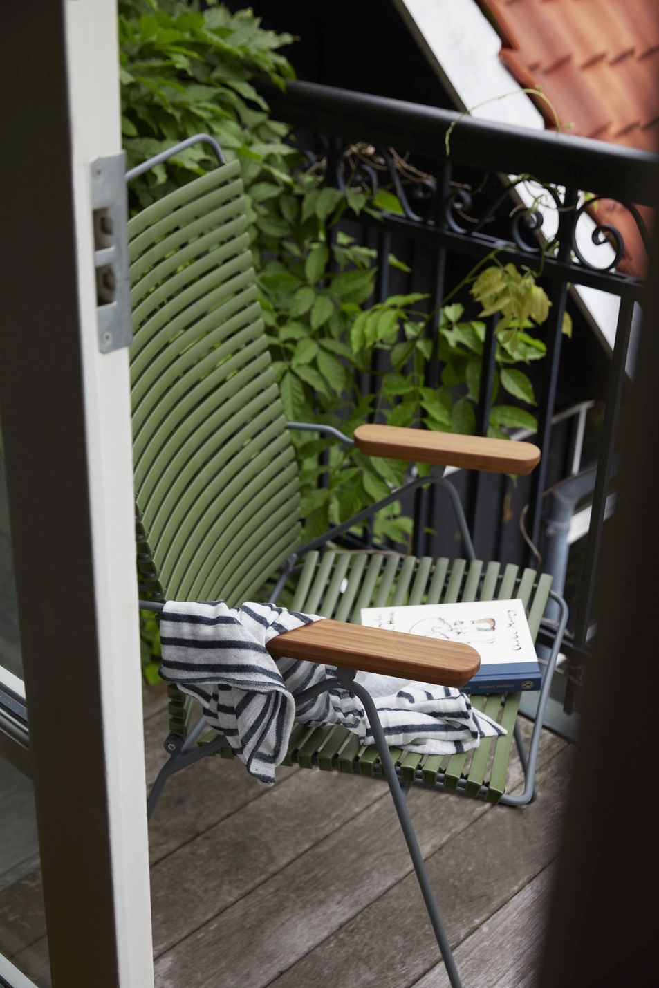 Grüner Click Position Chair Sessel von Houe für den Außenbereich auf einem Balkon.