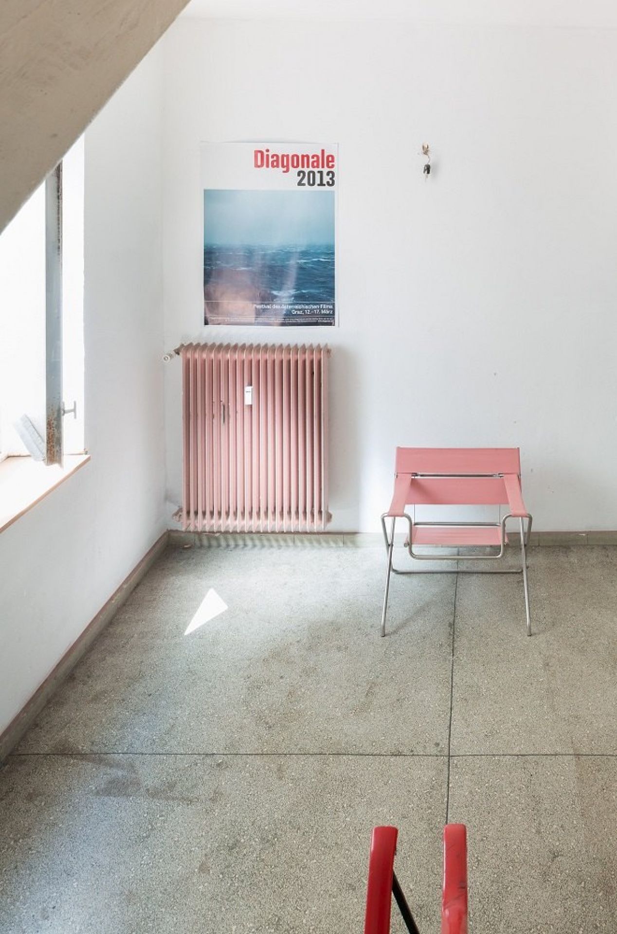 Rosa D4 Bauhaus Faltsessel von Tecta vor weißer Wand mit Heizkörper und Poster.