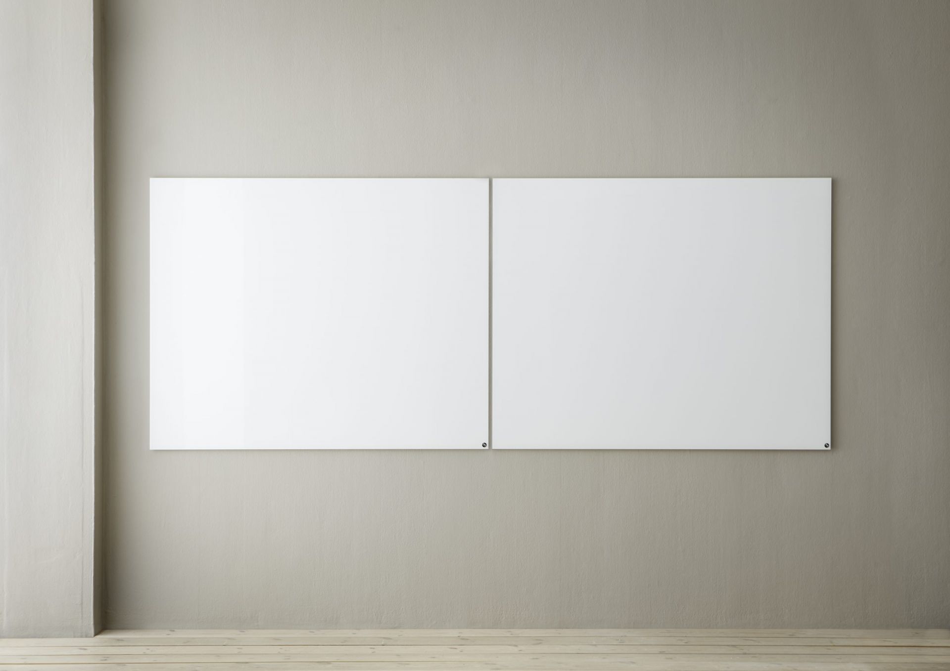 Zwei weiße, magnetische Chat Board Elements Glastafeln hängen an einer grauen Wand im minimalistischen Büro.