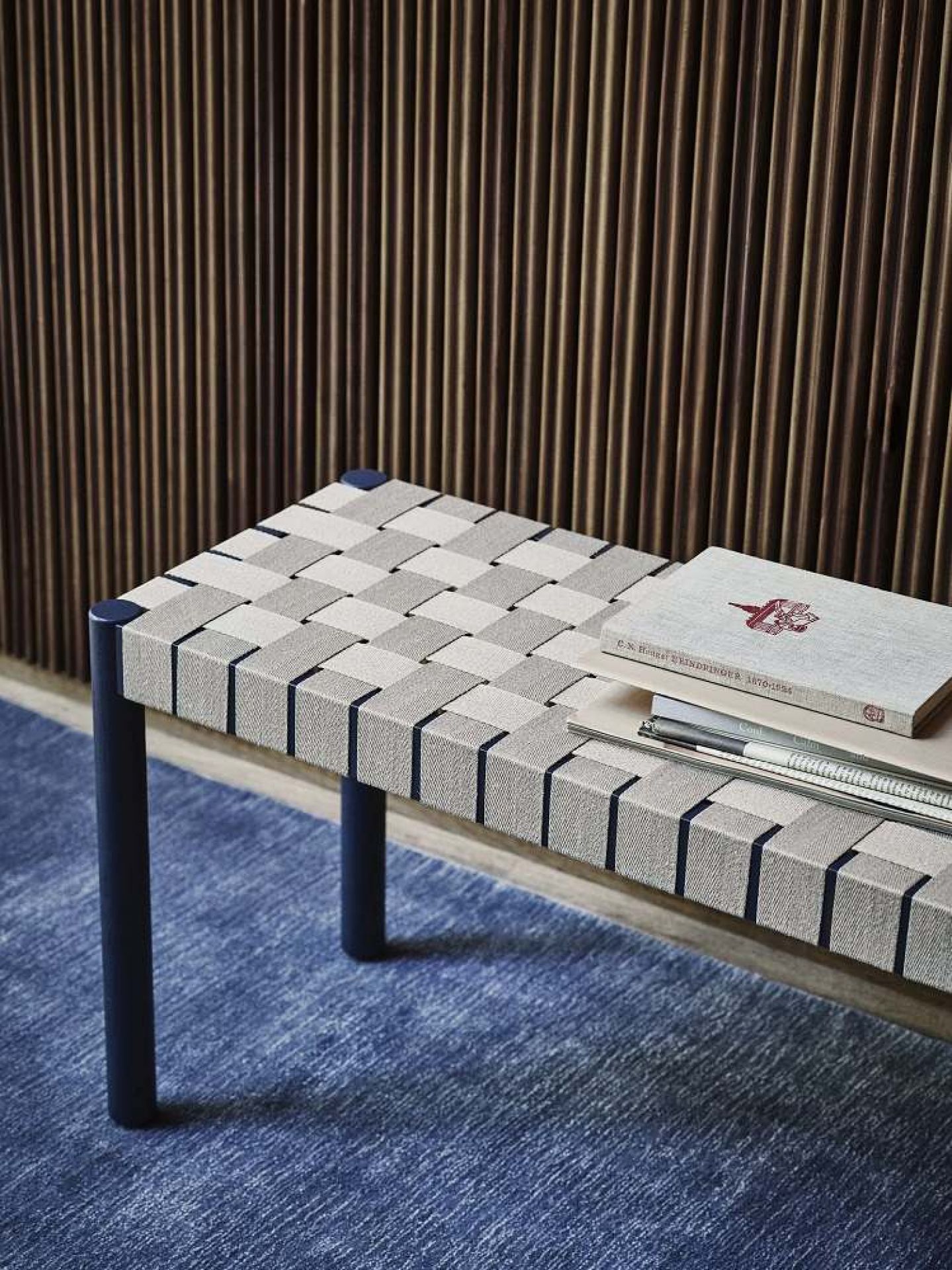 AndTradition Betty Bank TK4/TK5: Nahaufnahme einer modernen Sitzbank mit gewebter Sitzfläche und blauen Beinen.