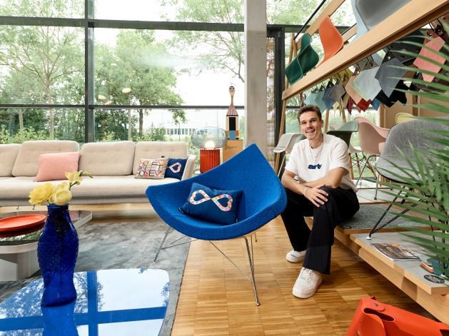 Blauer Coconut Chair von Vitra mit Mann im Hintergrund in einem modern eingerichteten Wohnzimmer.