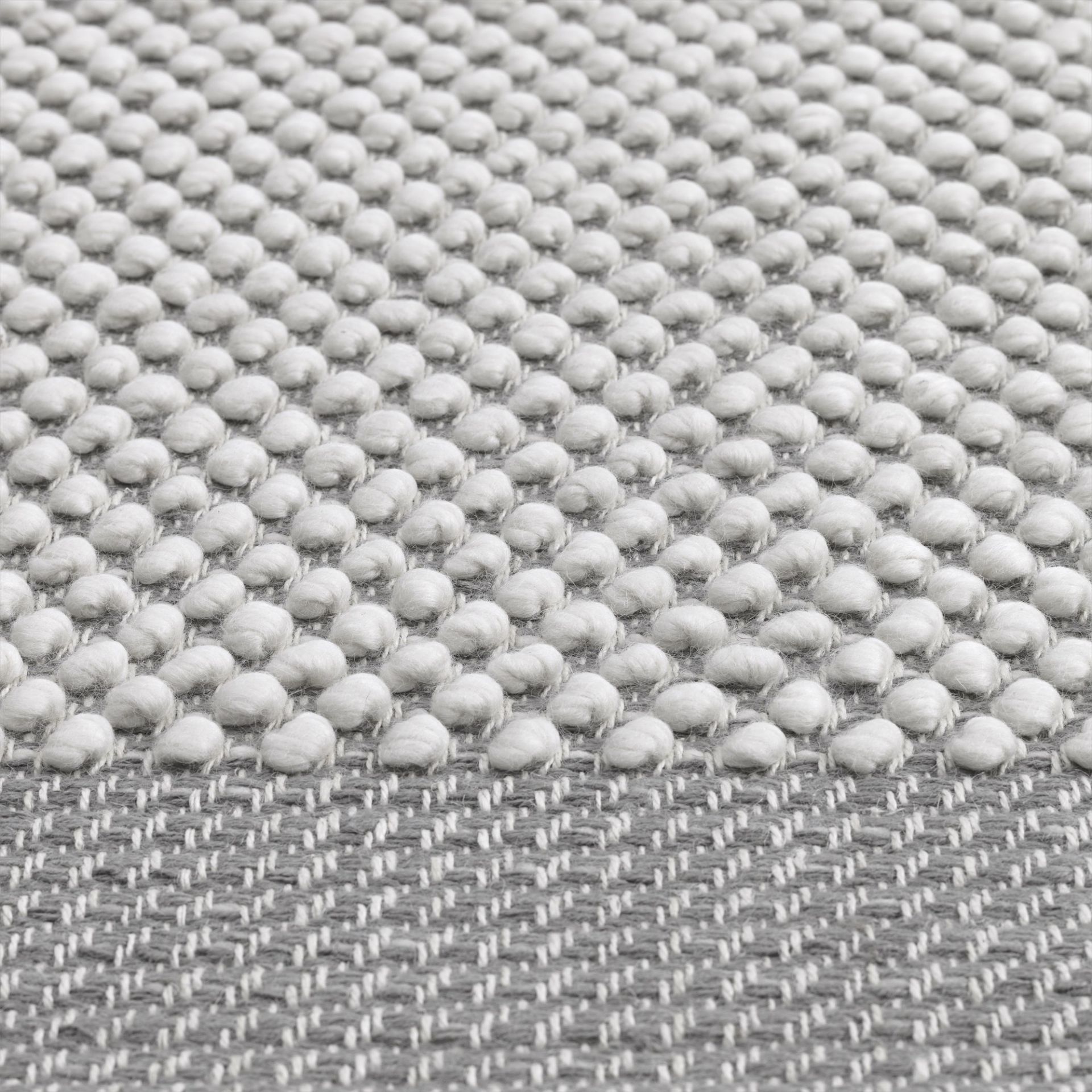 Detailaufnahme des Muuto Pebble Rug Teppichs in Grau mit erhabener, strukturierter Oberfläche für Wohnzimmer und Schlafzimmer.