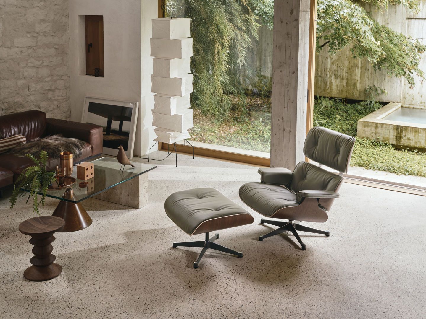 Eames Lounge Chair mit Ottoman in grauem Leder im modernen Wohnzimmer mit Designermöbeln.