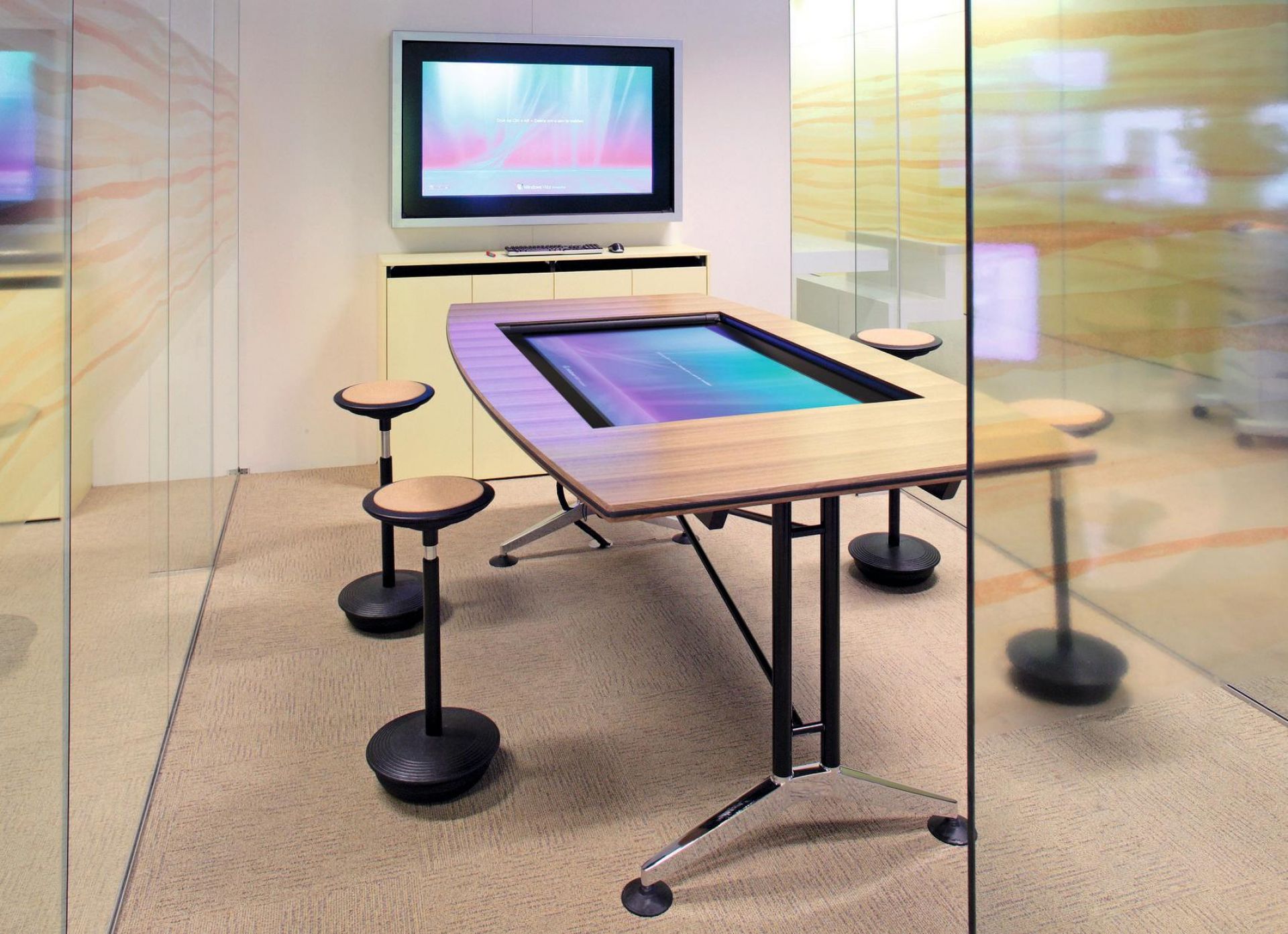Besprechungsraum mit interaktivem Tisch und vier Wilkhahn Stitz Stehhockern für ergonomisches, dynamisches Sitzen.