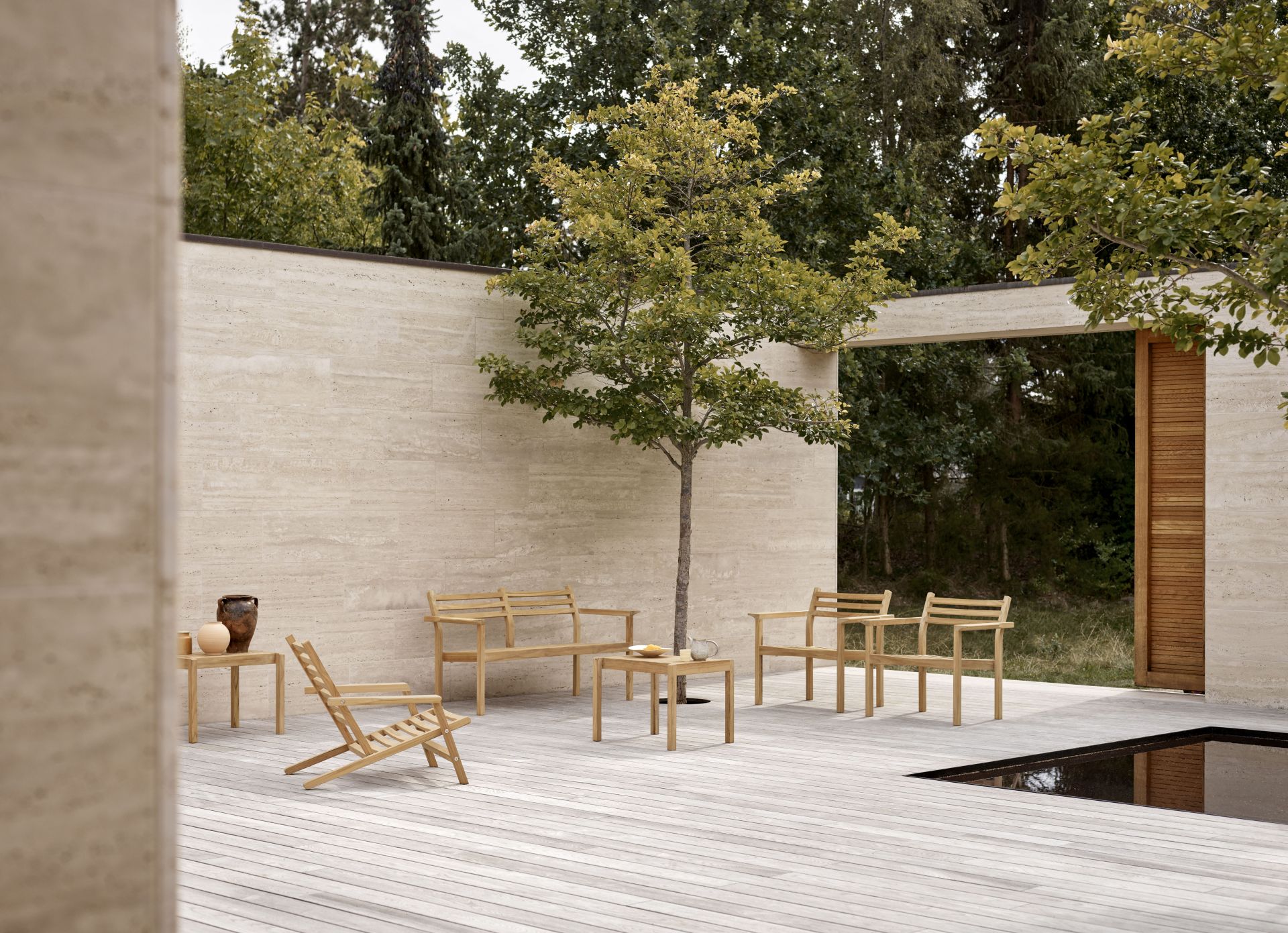 AH601 Teak Armlehnstuhl von Carl Hansen & Søn im Outdoor-Bereich mit weiteren Teakmöbeln.