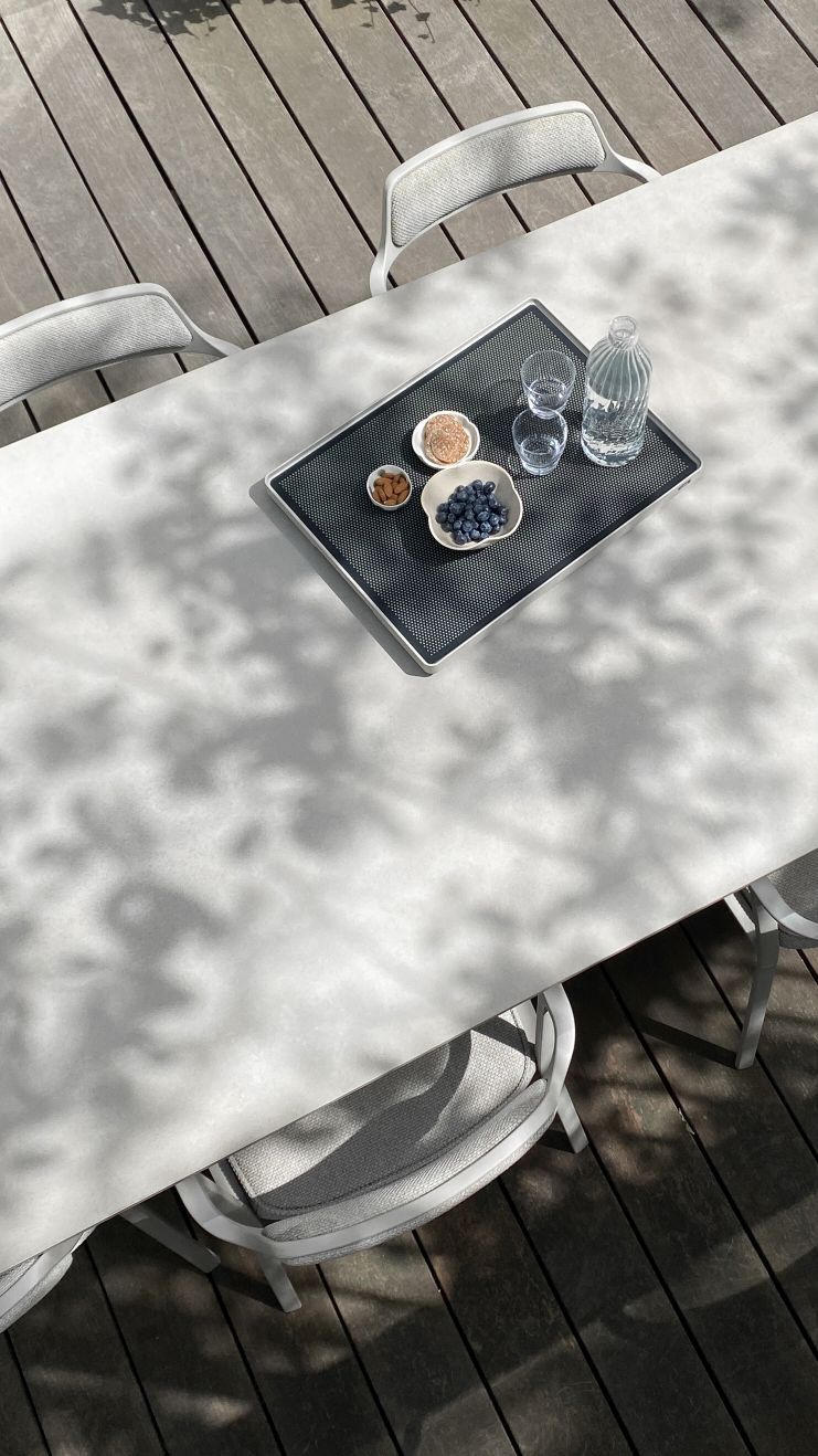 Vipp Outdoor Tisch mit Tablett, Getränken und Snacks im Freien auf einer Holzterrasse.