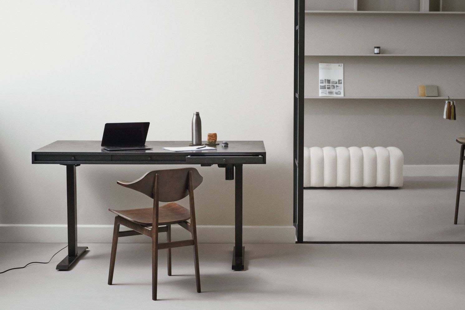 NORR11 Bufala Dining Chair aus Holz vor einem Schreibtisch mit Laptop im modernen Büro.