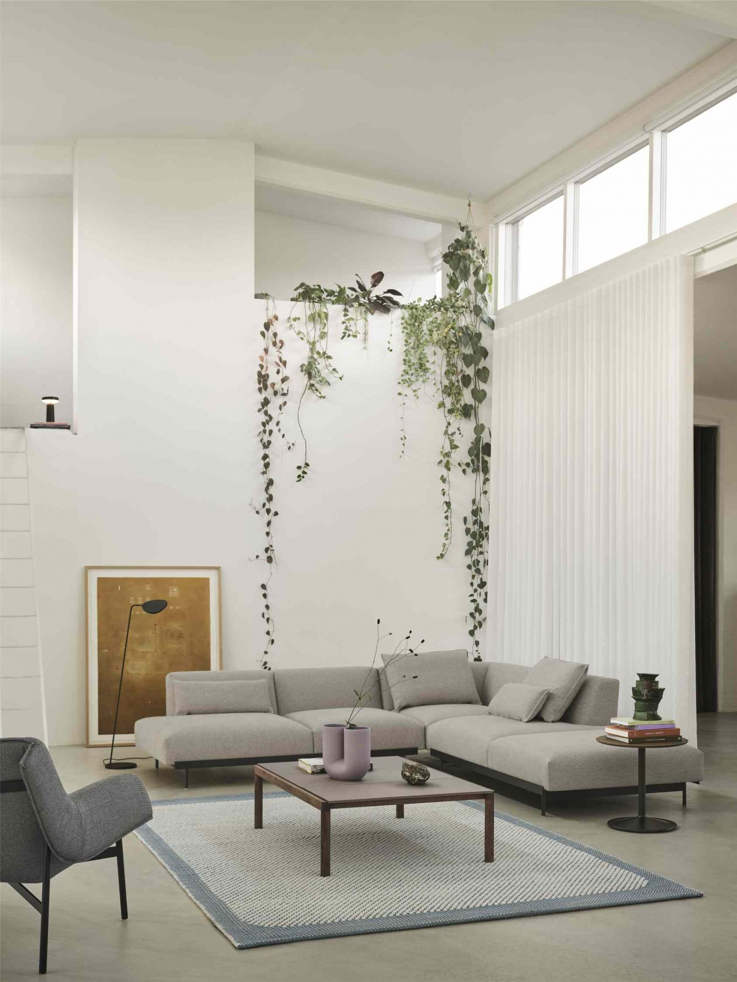 Muuto Couple Couchtisch aus Holz vor grauer Wohnlandschaft mit Dekoration und Teppich.