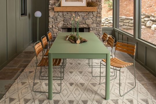 Fermob Surprising Teak Chair Outdoor: Detailaufnahme von Holzstühlen und einem grünen Tisch auf einem gemusterten Teppich.