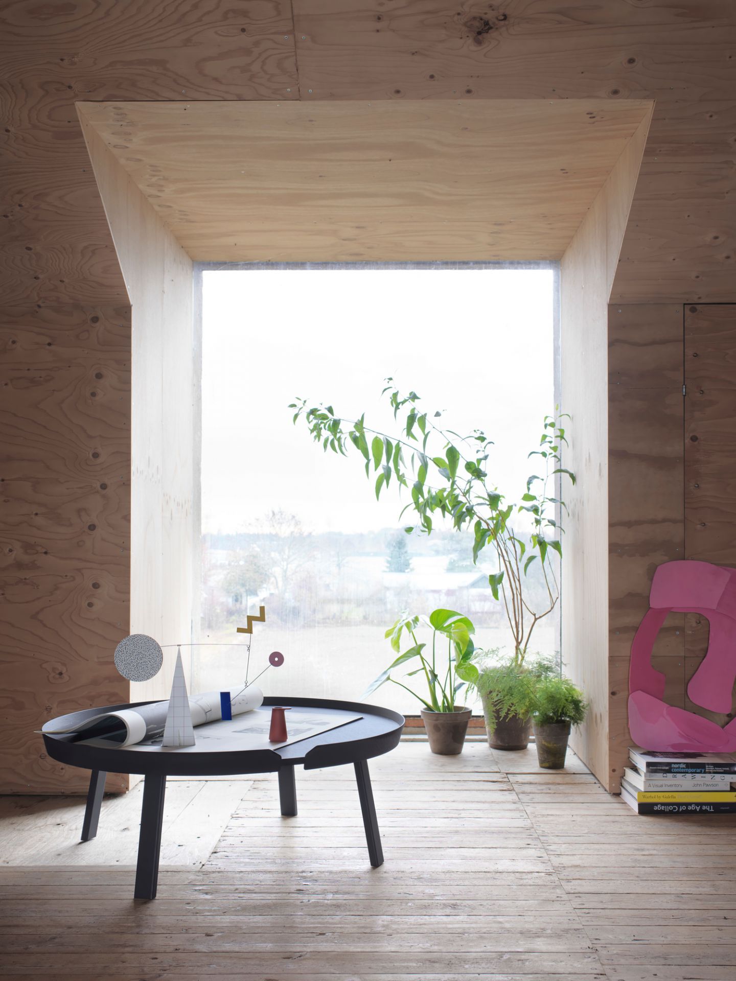 Muuto Around Coffee Table Extra Large in dunklem Holz, dekoriert mit Kunstobjekten in hellem Raum.