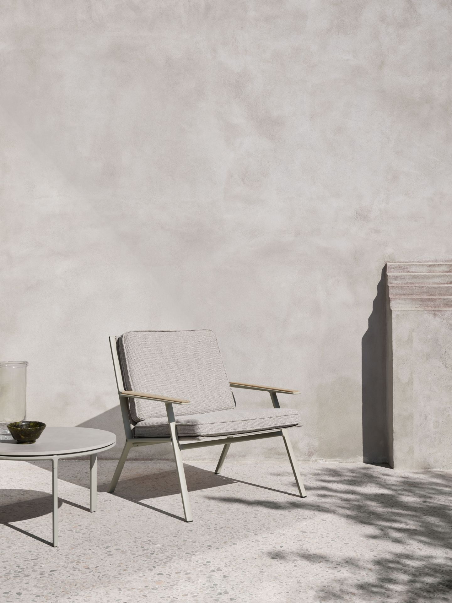 Heller Vipp Outdoor Lounge Stuhl mit Armlehnen und Tisch auf einer Terrasse.