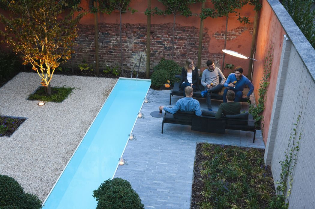 Gruppe sitzt auf Sol + Luna Outdoor Sofa-Sonnenliegen von Extremis im Garten mit Pool.
