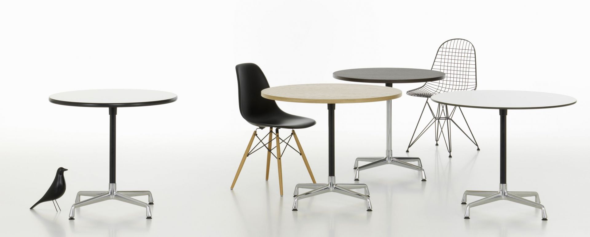 Produktbild: Mehrere runde Eames Contract Table Tische von Vitra mit verschiedenen Tischplatten und Stühlen.
