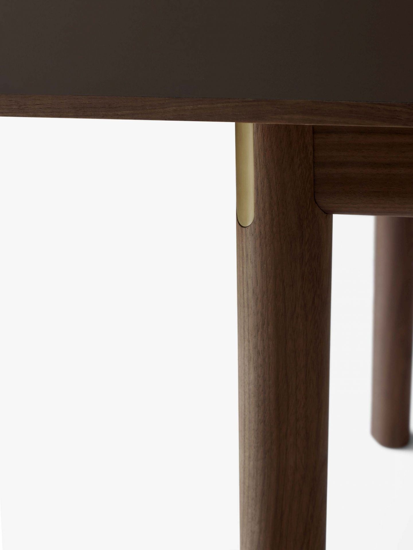 Detailaufnahme des AndTradition Patch HW1 Esstisches: Dunkelbraune Tischplatte und Tischbeine aus Holz mit Messingdetails.