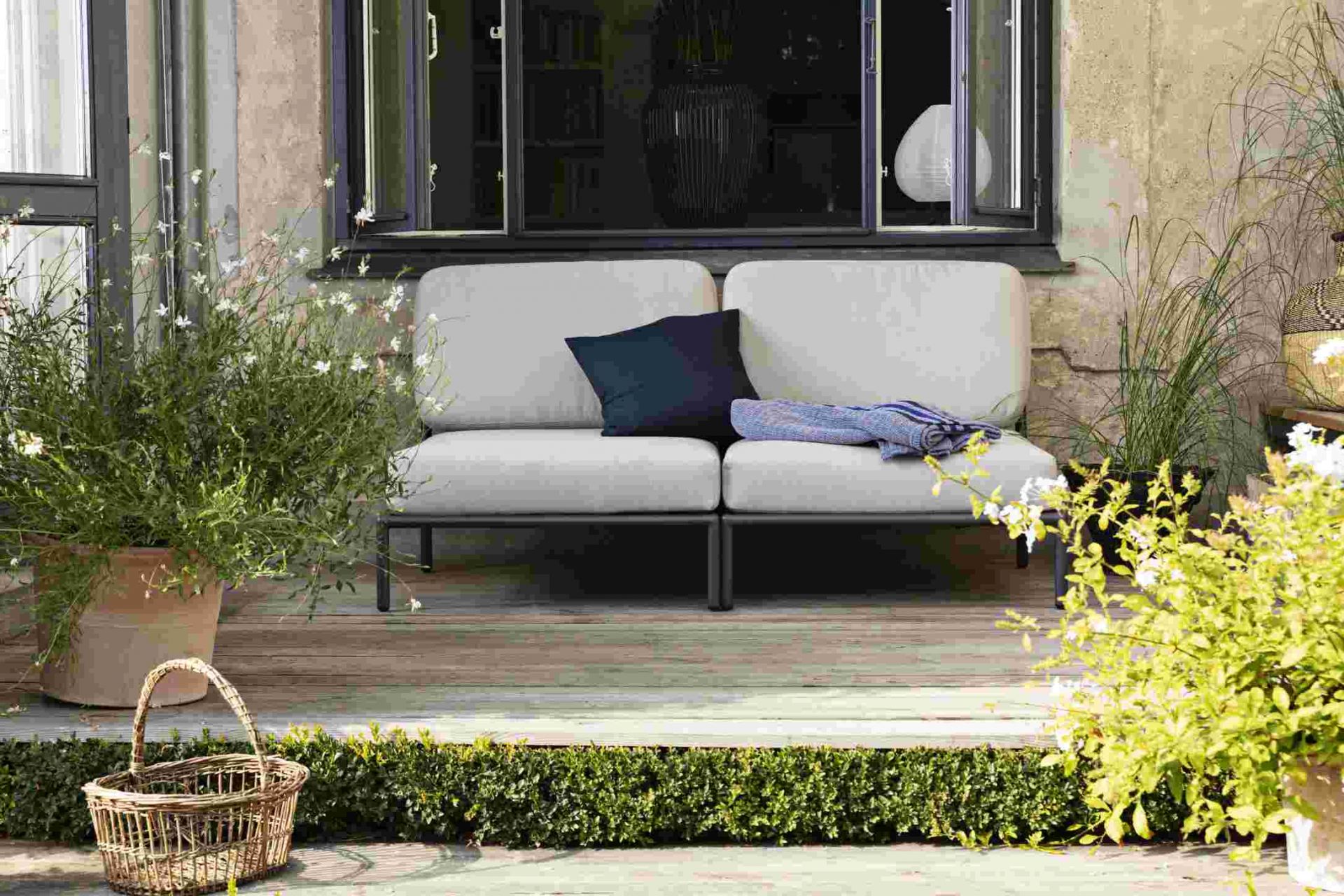 Houe Level Lounge Sessel für den Außenbereich auf einer Terrasse mit Pflanzen.