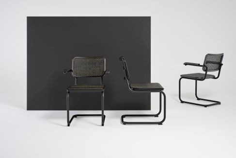 Drei schwarze S 64 V Stahlrohr Freischwinger Stühle von Thonet mit Wiener Geflecht vor schwarzem Hintergrund.