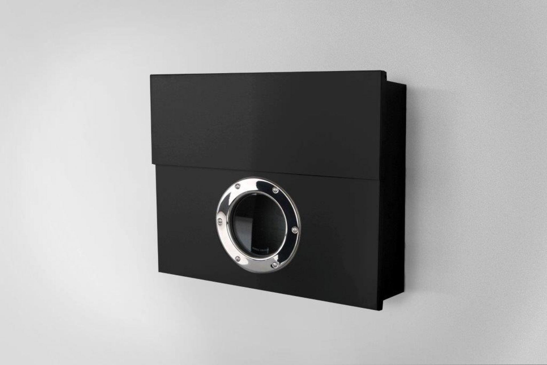 Schwarzer Briefkasten mit Bullauge aus Edelstahl an einer weißen Wand, moderne Hauspostkasten-Design.