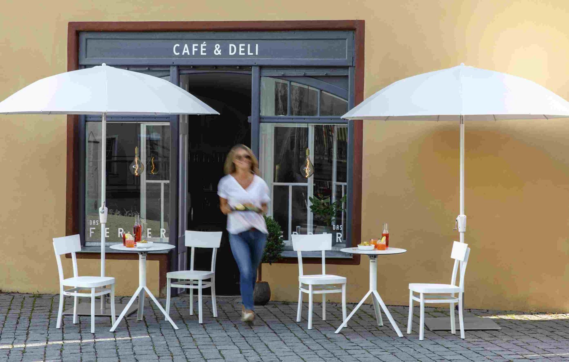 Weishäupl Sonnenschirm, Pagodenschirm in Weiß vor Café mit Tischen und Stühlen.