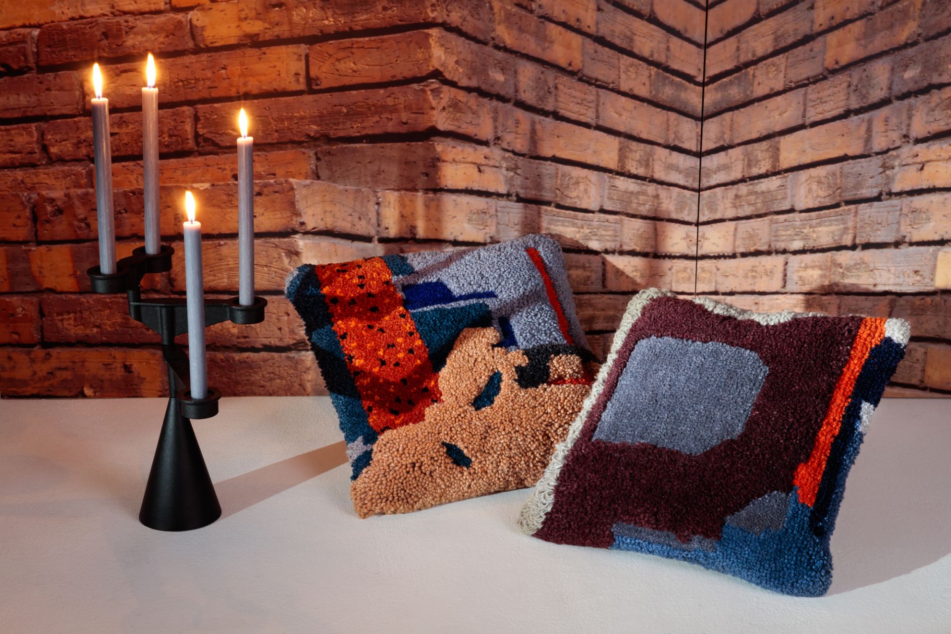 Spin Candelabra Mini Kerzenständer von Tom Dixon mit brennenden Kerzen und zwei dekorativen Kissen.