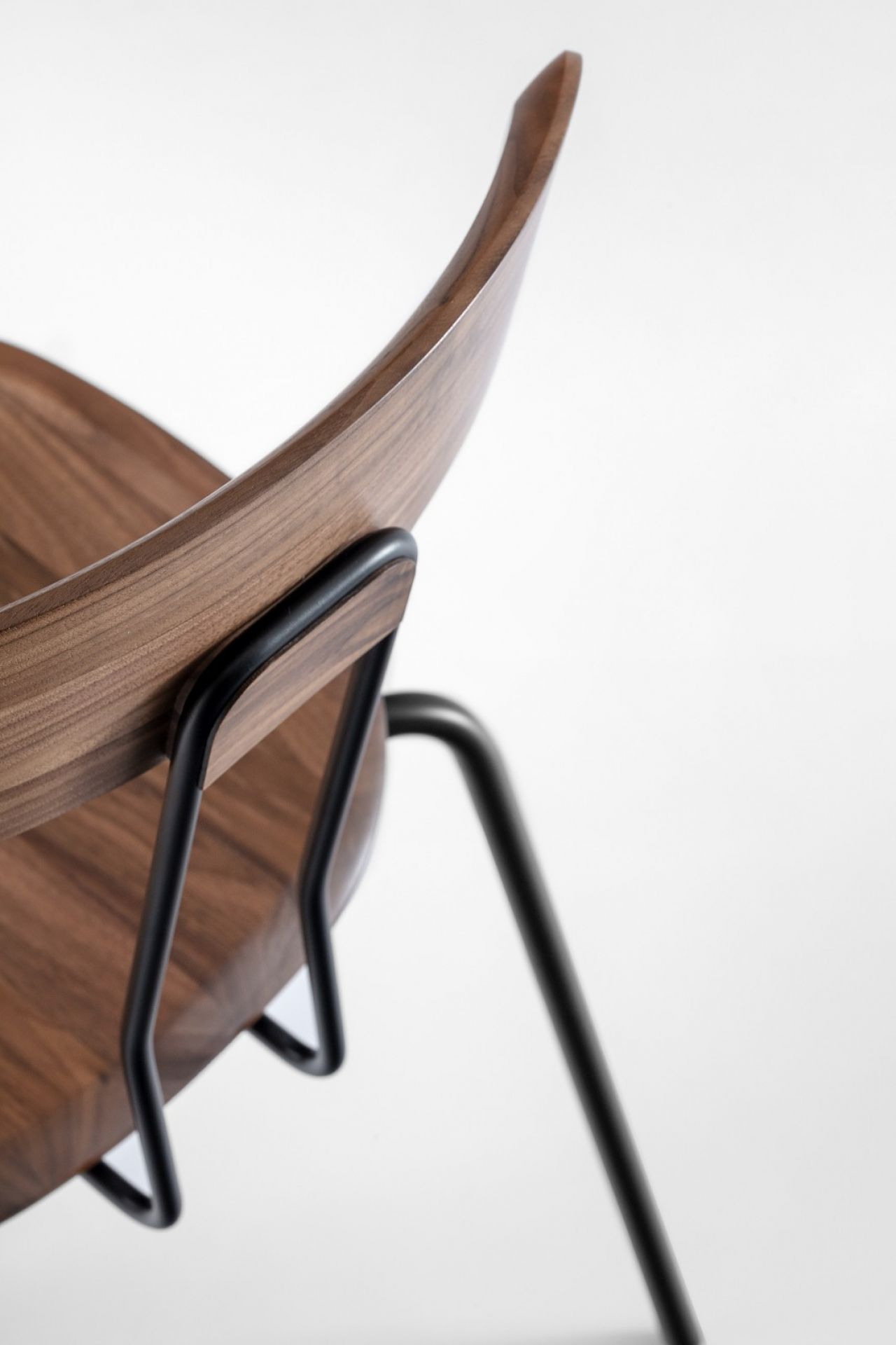 Detailaufnahme des Okito Chair Stuhls von Zeitraum mit dunklem Holz und schwarzen Metallbeinen.