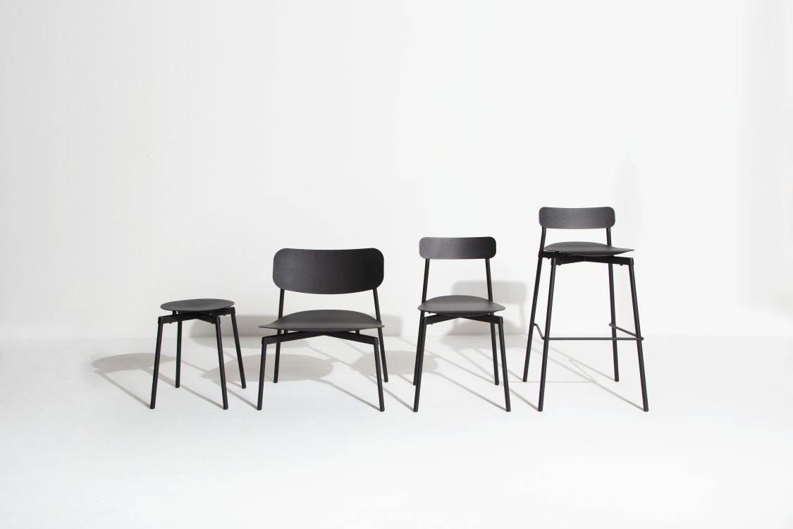 Vier schwarze Stühle und ein Hocker mit minimalistischem Design auf weißem Hintergrund.