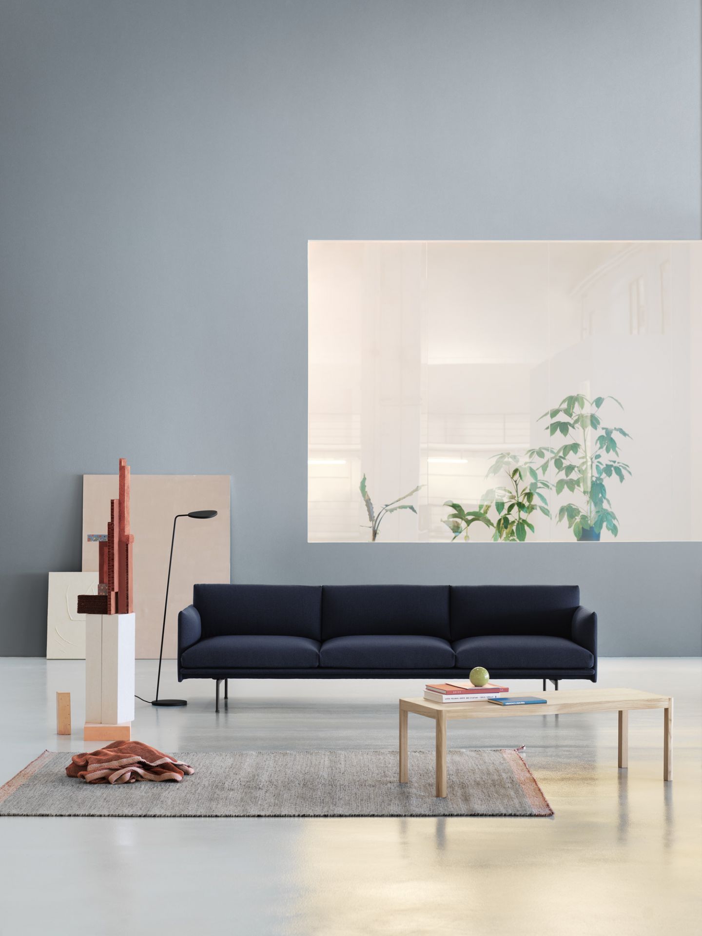 Muuto Workshop Couchtisch aus Eiche vor blauem Sofa und grauem Teppich im modernen Wohnzimmer.