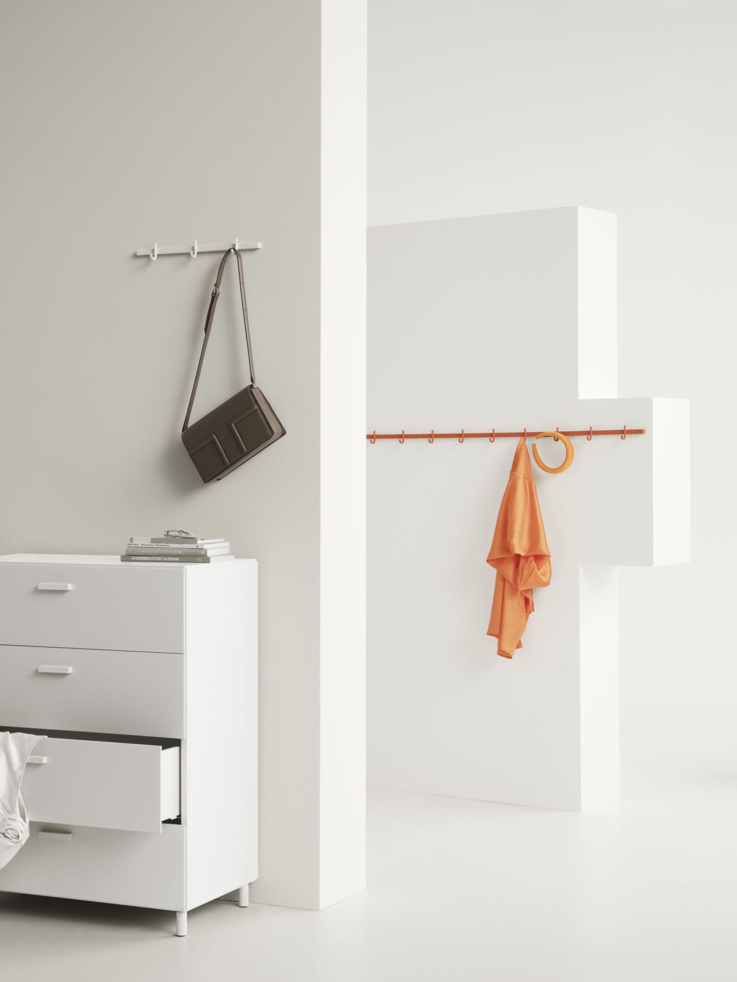 Weiße Relief Hakenleiste von String Furniture, 123cm breit, mit Tasche und Kleidung an der Wand.