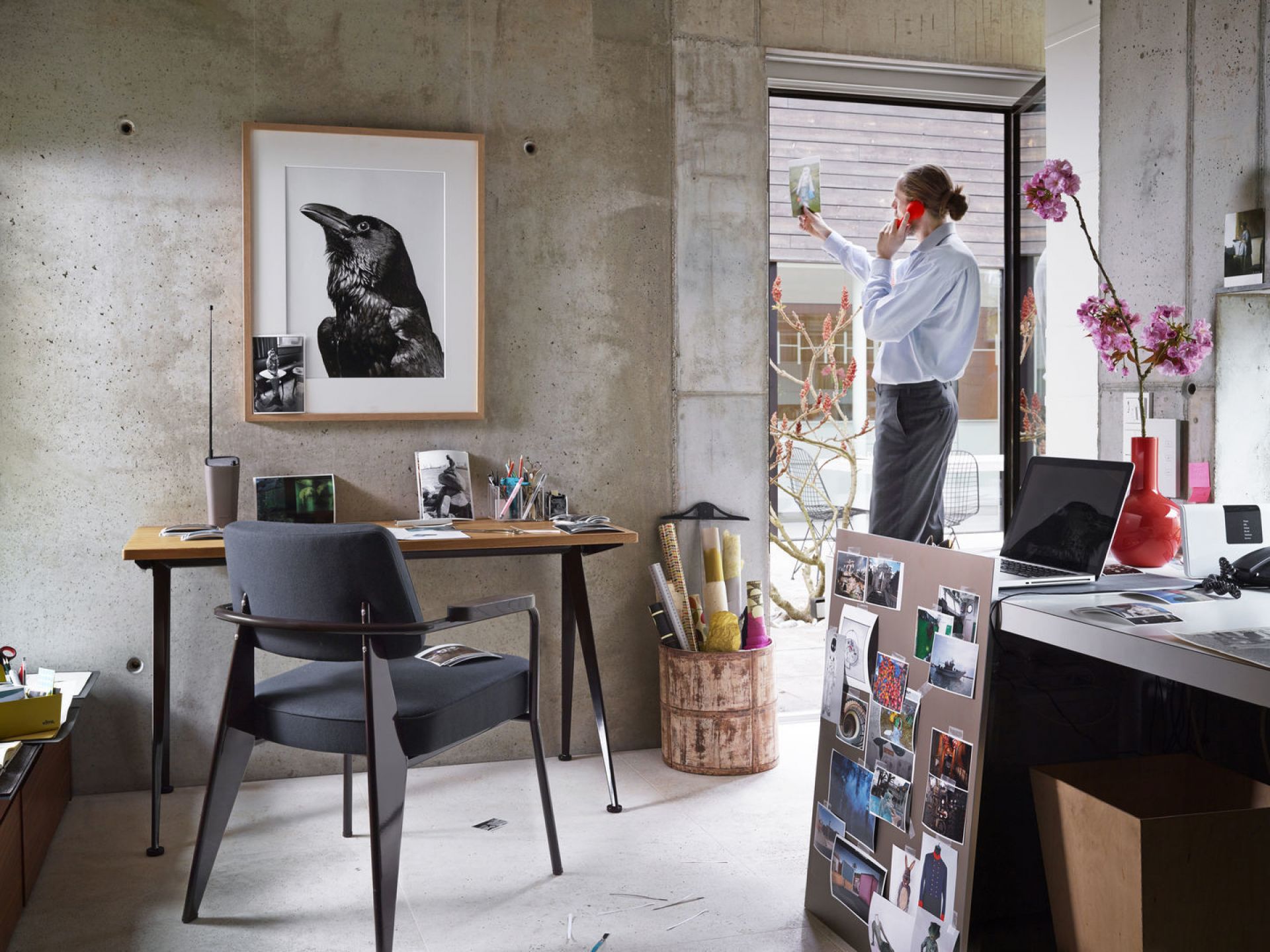 Vitra Fauteuil Direction Sessel in grau vor Schreibtisch in modernem Büro mit Betonwand.