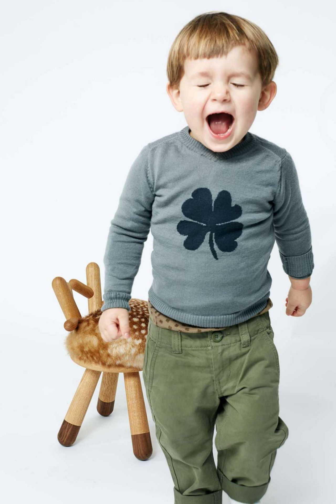 Schreiender Junge neben Bambi Chair Kinderstuhl aus Holz mit Fellimitat, skandinavisches Design.