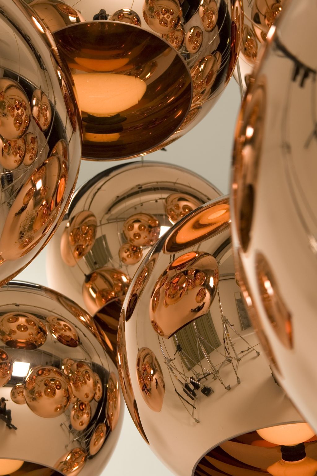Nahaufnahme von mehreren modernen Pendelleuchten aus Kupfer mit reflektierenden Oberflächen für stilvolle Innenbeleuchtung.