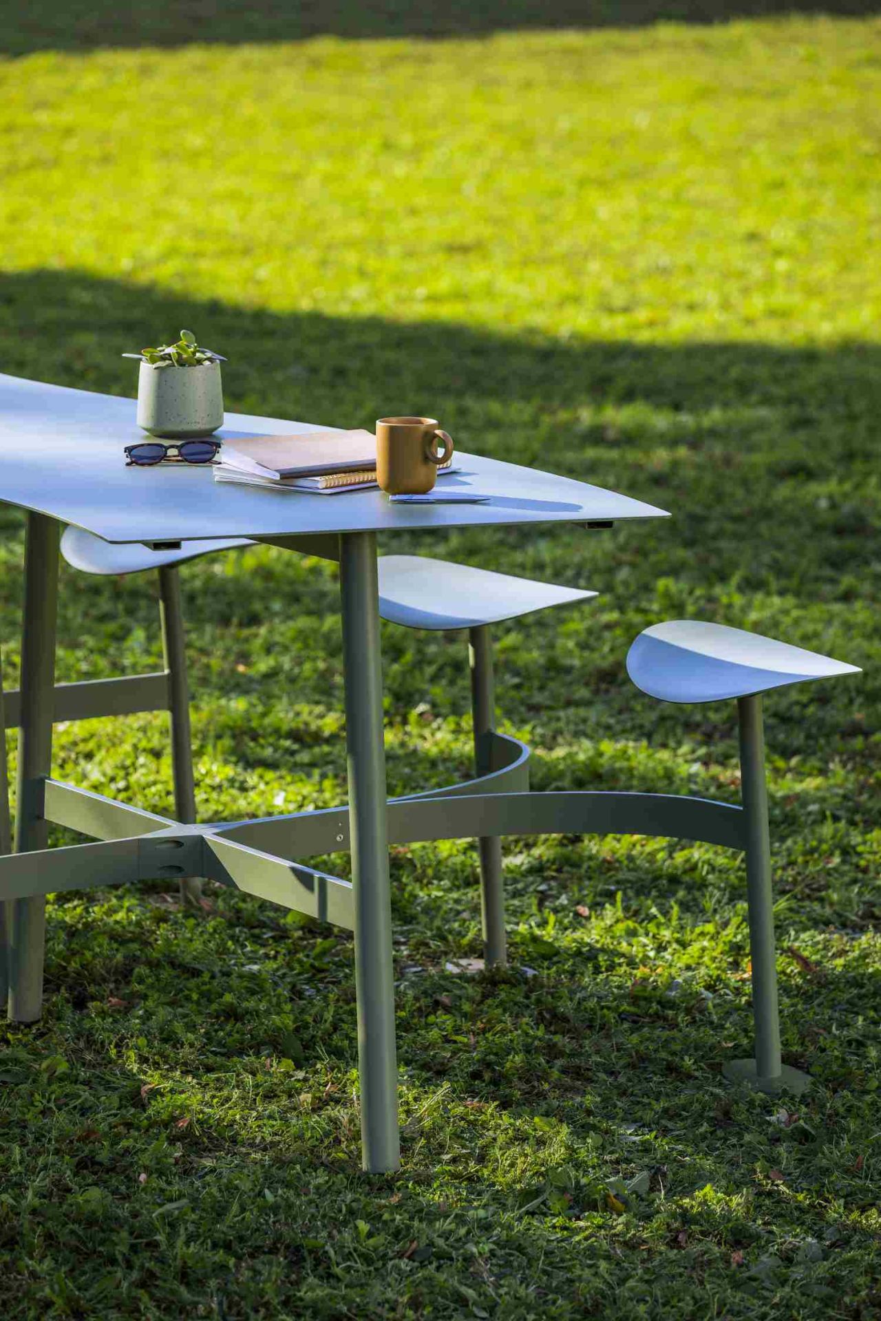 Fermob Bolder Theke Outdoor auf Rasen mit Kaffeetasse, Notizbuch und Sonnenbrille für entspanntes Arbeiten im Freien.