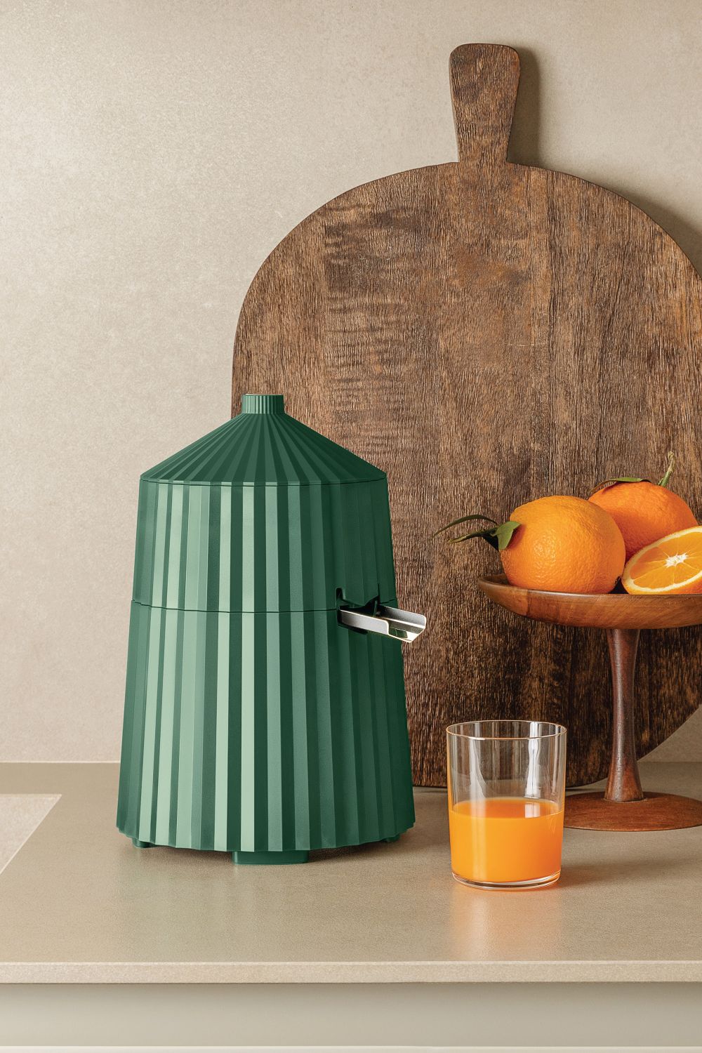 Grüne Alessi Zitronenpresse MDL07 Plissé: Elektrischer Entsafter mit Glas Orangensaft und frischen Orangen.