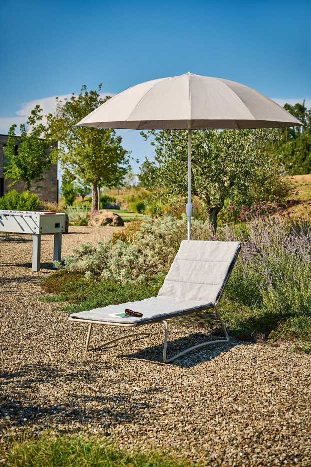 Weishäupl Sonnenschirm Pagodenschirm über einer Sonnenliege im Garten, der Schatten spendet an einem sonnigen Tag.