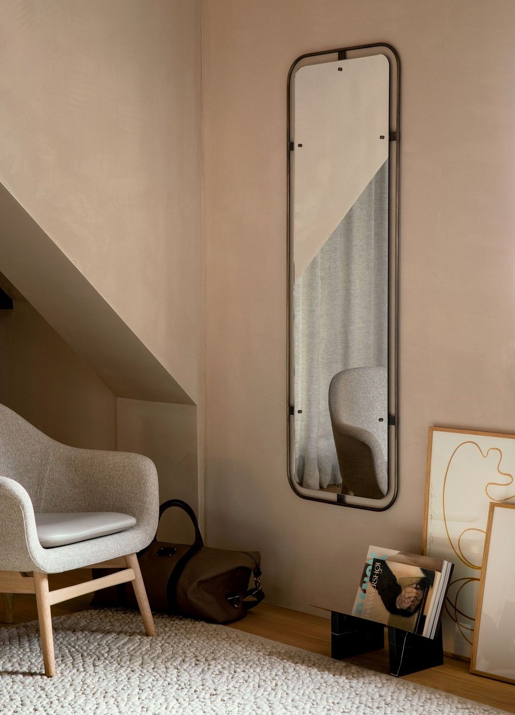 Audo Copenhagen Gravel Rug Teppich in hellem Wohnraum mit Sessel und Spiegel.
