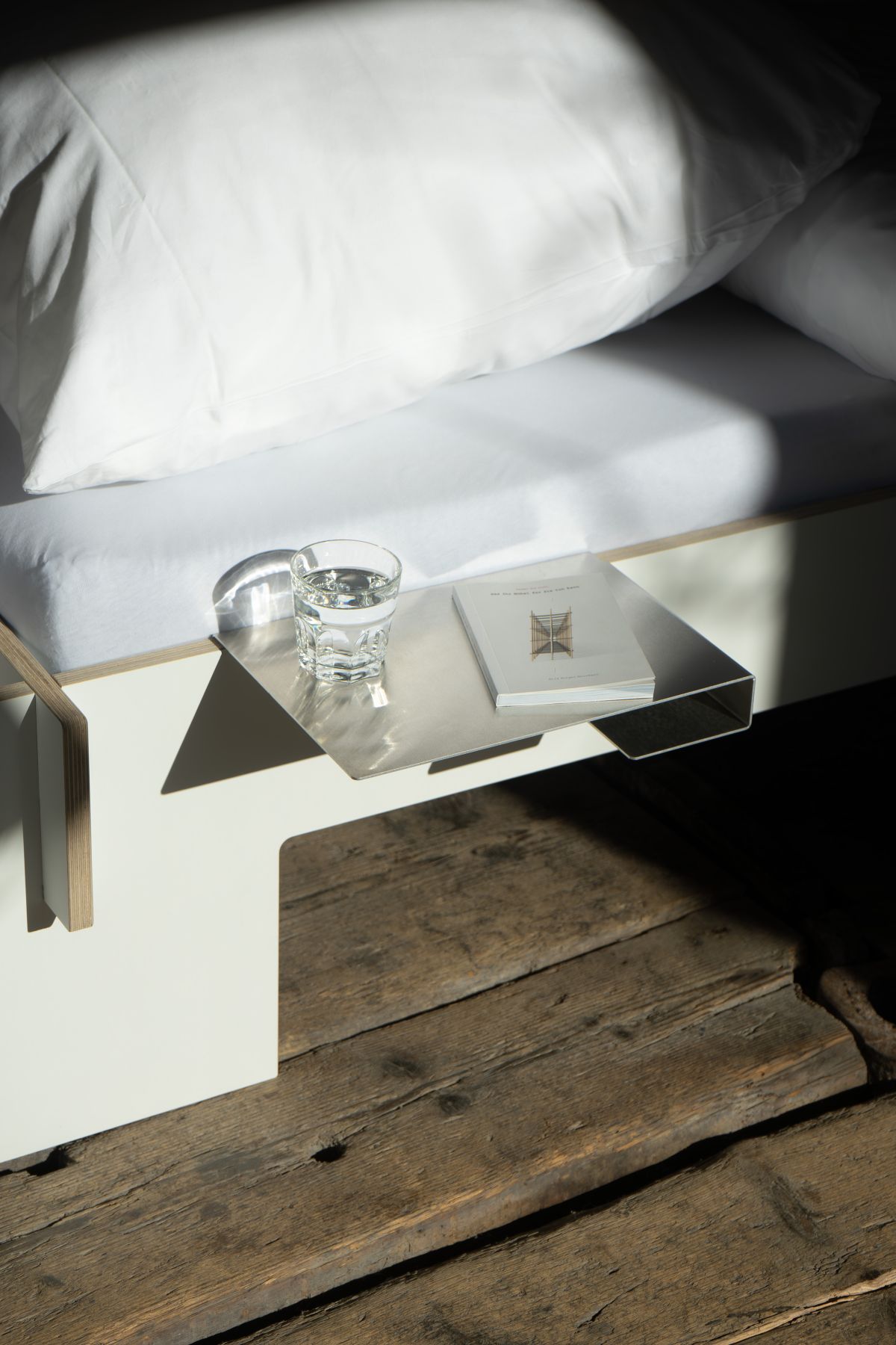 Bett mit Moormann Bettkante Leicht Ablage, darauf Buch und Glas Wasser.