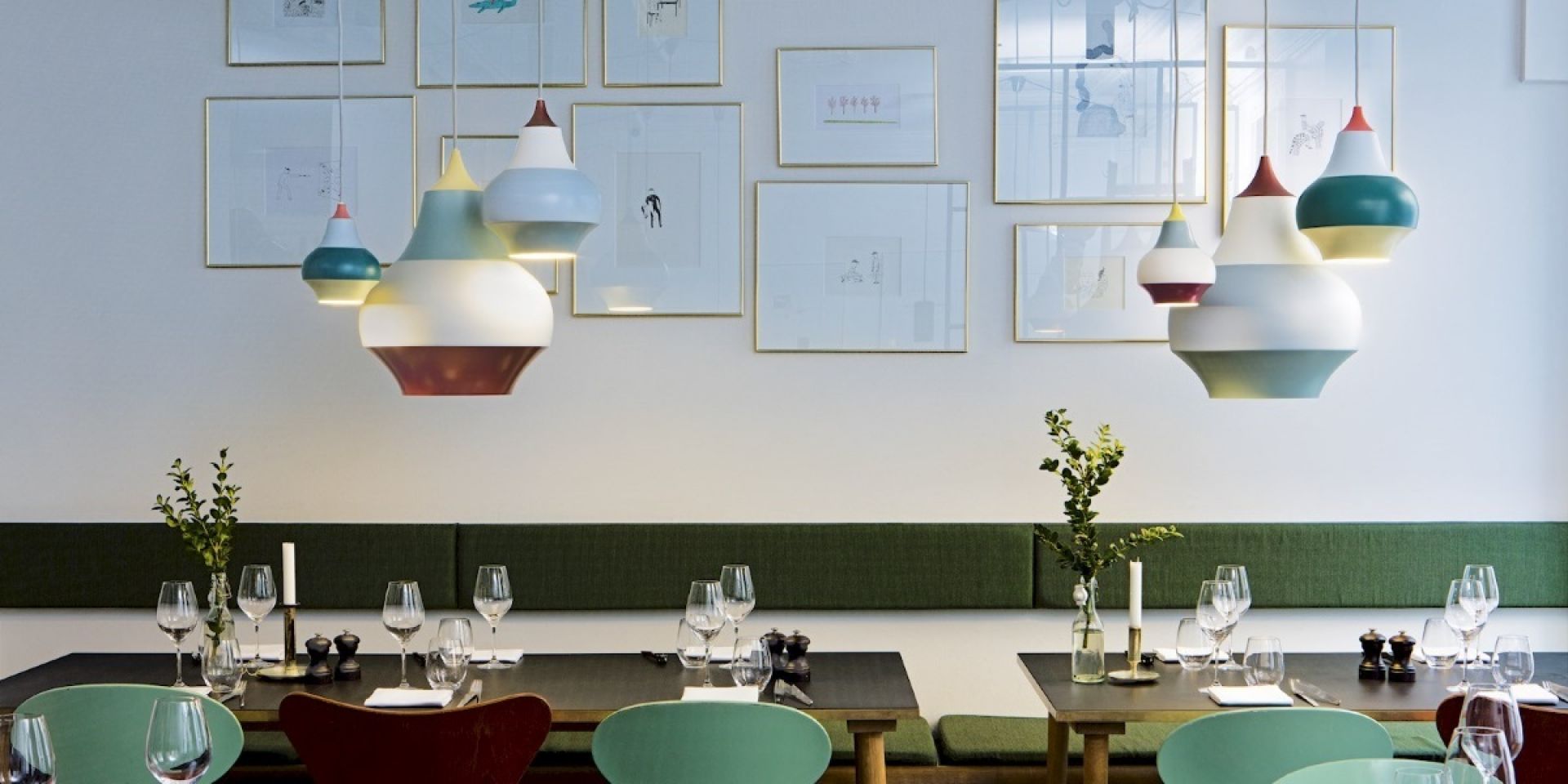 Cirque Pendelleuchten von Louis Poulsen über einem gedeckten Esstisch in einem Restaurant mit Kunst an der Wand.